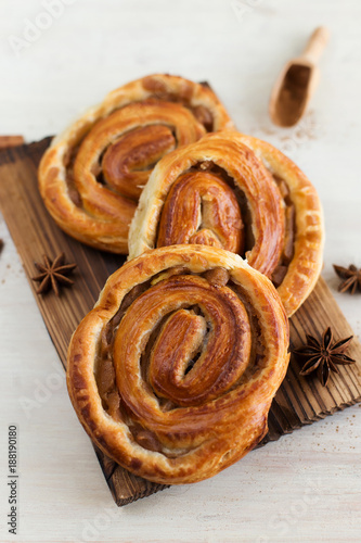 Cinnamon rolls, decorated with spices, on a light background (close-up)