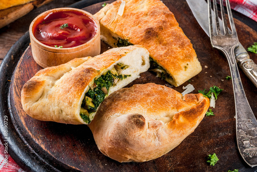 Fotografija Italian food, closed pizza calzone with Spinach and Cheese, wooden background, c