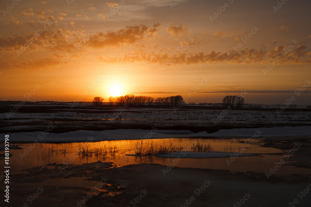 the onset of early spring. orange sunset on the background of the river and snow.