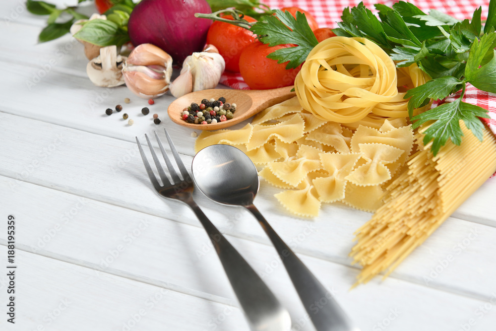 Pasta spaghetti, farfalle, linguine with vegetables and spices on white wooden table Pasta spaghetti, farfalle, linguine with vegetables and spices on white wooden table