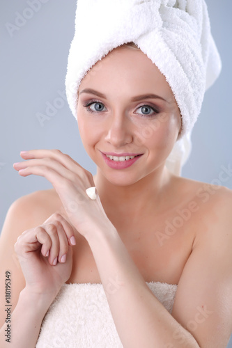 Young woman putting cream on her hand Isolated on gray background. Young woman