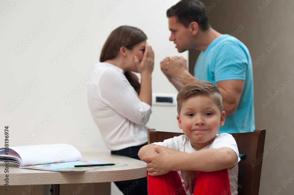 Domestic violence. Little boy looking at the camera while mother and father quarrel - husband beats his frightened wife