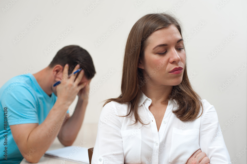 Portrait of successful self-sufficient positive beautiful woman standing against background of blurred sad man on white background Portrait of successful self-sufficient positive beautiful woman standing against background of blurred sad man on white background