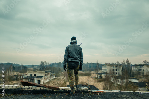 a man with tactical equipment standing on the top of abandoned building
