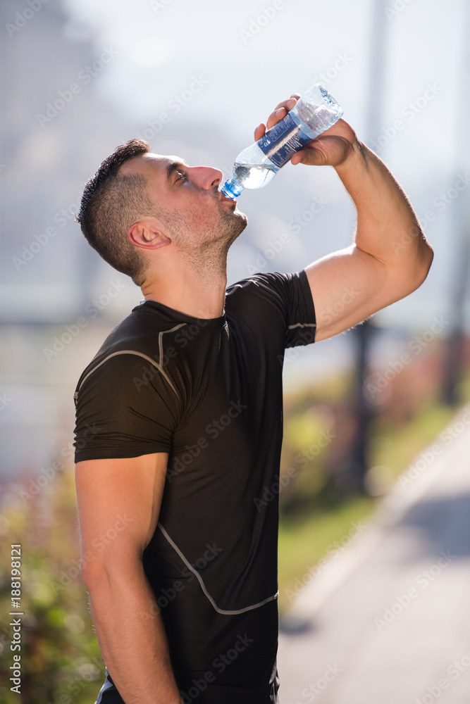 man drinking water from a bottle after jogging