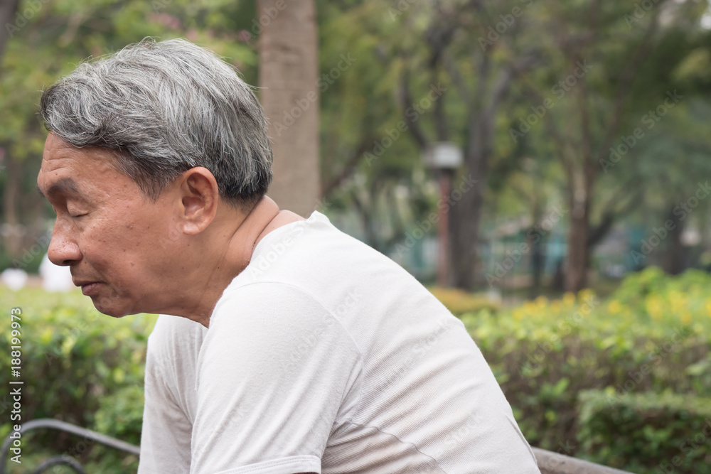 sad hopeless frustrated old retired senior man sitting in public park, urban poverty concept