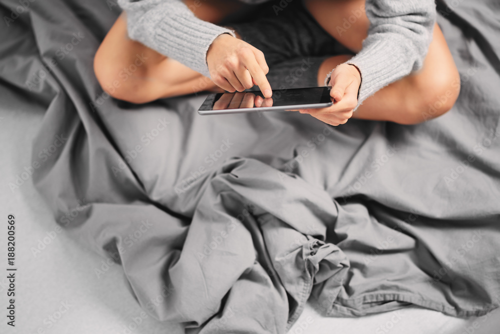 Girl sitting on bed in morning and using tablet