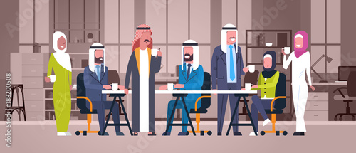 Group Of Arabic Business People Drink Tea Or Coffee Sit Together At Desk In Modern Office Muslim Workers Team At Break Flat Vector Illustration