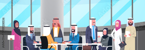 Group Of Happy Smiling Arabic Business People Working Together In Office Sit At Desk Muslim Workers Team Brainstorming Meeting Flat Vector Illustration
