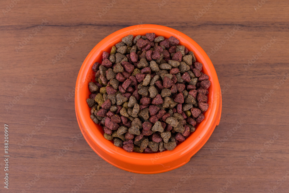 Dry cat food in bowl on wooden background. Pet food on wood surface. Top view Dry cat food in bowl on wooden background. Pet food on wood surface. Top view