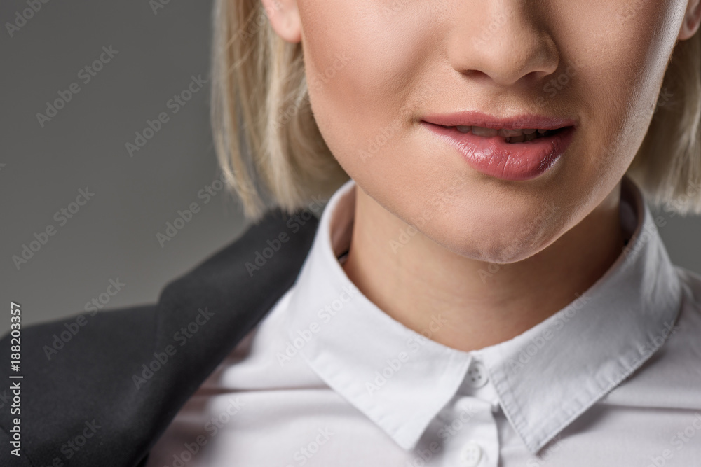 cropped shot of woman in white shirt biting lip isolated on grey cropped shot of woman in white shirt biting lip isolated on grey