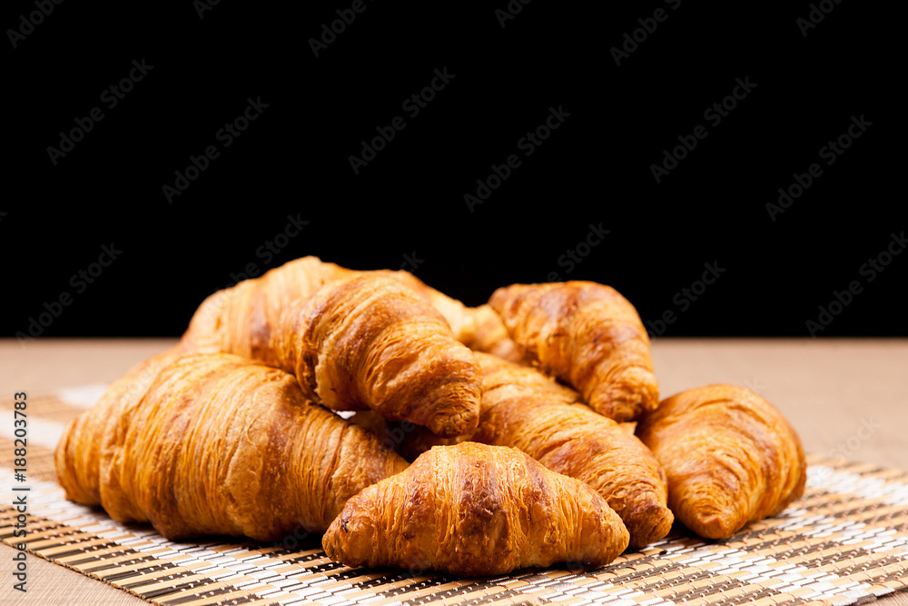 Freshly baked croissants lying on a table over a black background