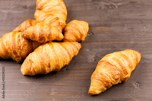 Fresly baked golden croissants lying on a wooden table photo