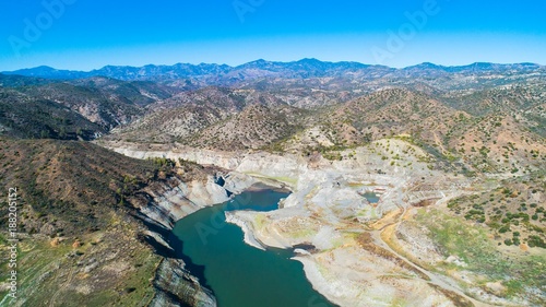 Aerial bird eye view of Kalavasos rockfill dam, Larnaca, Cyprus. The Vasilikos river streaming towards the reservoir and the hills around the water from above.