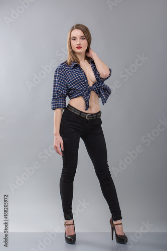 stylish girl in a cowboy shirt without a bra on a grey background