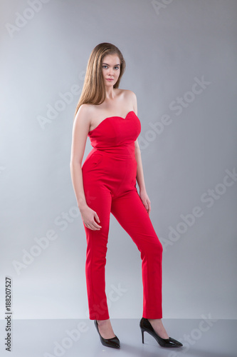 Young beautiful plus size model wearing in red costume, xl woman on gray studio background