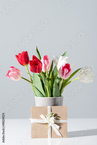 close-up view of beautiful blooming tulip flowers in vase and envelope on grey