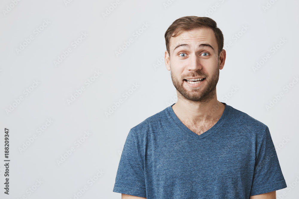 Shocked stunned emotional young man with stubble and bugged eyes, being troubled to listen advices of wife isolated against blank wall background. European male can`t believe in shocking news Shocked stunned emotional young man with stubble and bugged eyes, being troubled to listen advices of wife isolated against blank wall background. European male can`t believe in shocking news