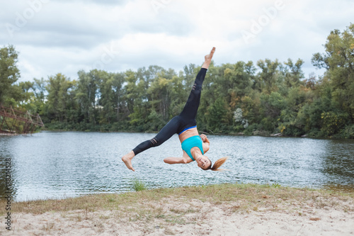 Girl is engaged in sports in nature. She makes a roll and stretch in the air