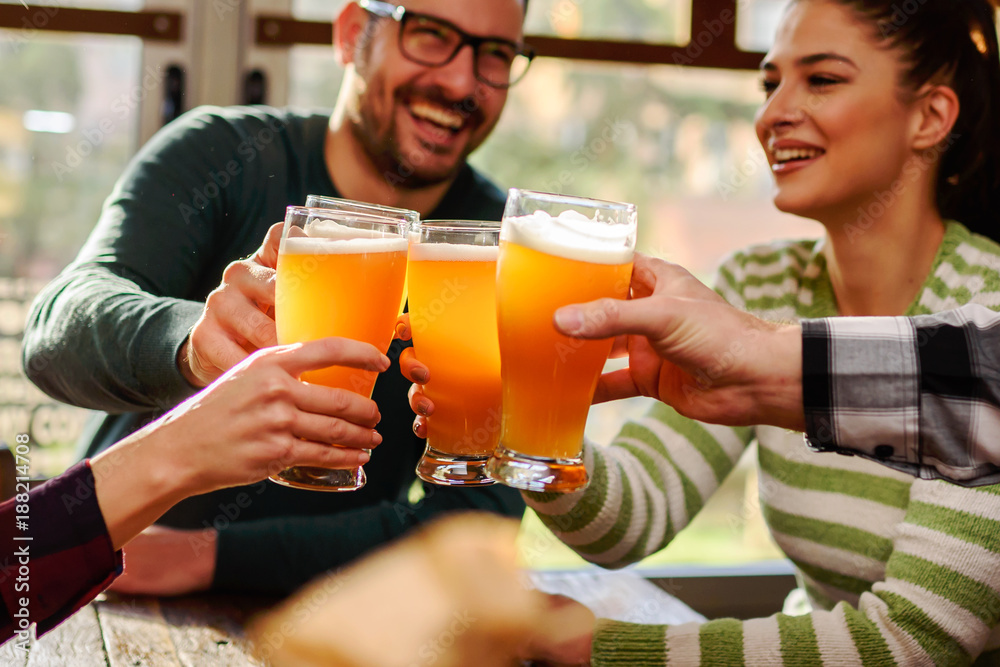 Smiling young people drinking craft beer in pub