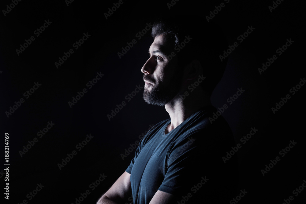 Handsome look. Handsome nice brutal man standing half face and looking in front of him while standing against black background