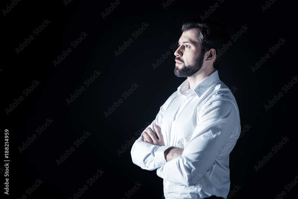Obraz premium Handsome look. Serious nice bearded man standing cross handed and looking in front of him while being thoughtful