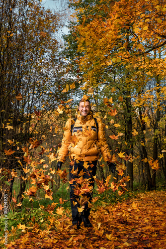 A man walking in the autumn forest plays with fallen leaves. The nature reserve of the valley of the river Skhodnya. Kurkino. Moscow. Russia. photo