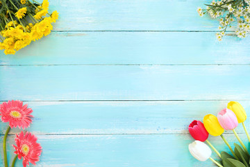 Colorful flowers bouquet on blue wooden background.  Concept flowers of spring, top view and border design,