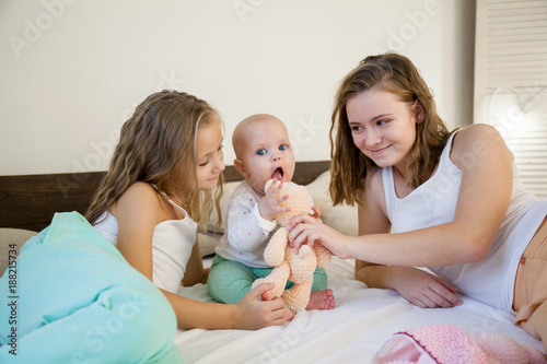 three sisters baby girl children in the morning on the bed in the bedroom photo