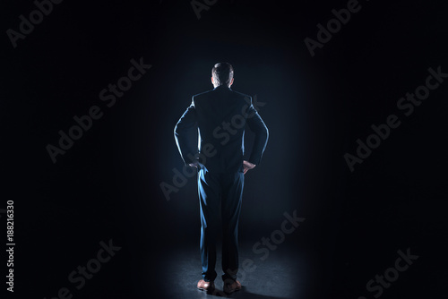 Smart businessman. Nice handsome serious man standing against black background and looking in front of him while testing new technology © Viacheslav Yakobchuk