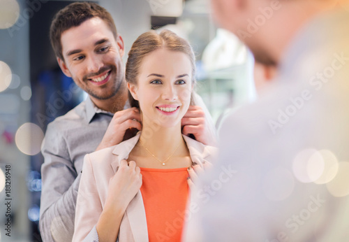 couple trying golden pendant on at jewelry store