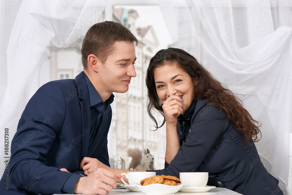 happy couple drinking coffee and having fun near window with a street view - travel and love concept