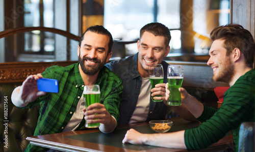 Fotografia friends taking selfie with green beer at pub