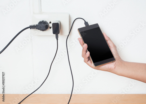 Hand holding a Mobile phone in charging plugged