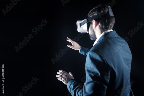 New reality. Smart handsome positive man looking in front of him and moving his hands while using 3d reality