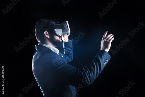 Exciting experience. Happy positive joyful man smiling and looking in front of him while enjoying being in virtual reality