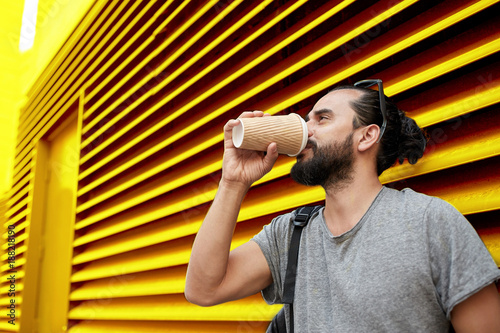 Vászonkép man drinking coffee from paper cup over wall
