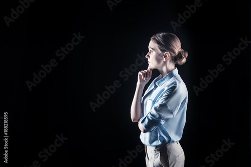 Pensive look. Nice attractive young woman standing and thinking while looking for a solution to the problem