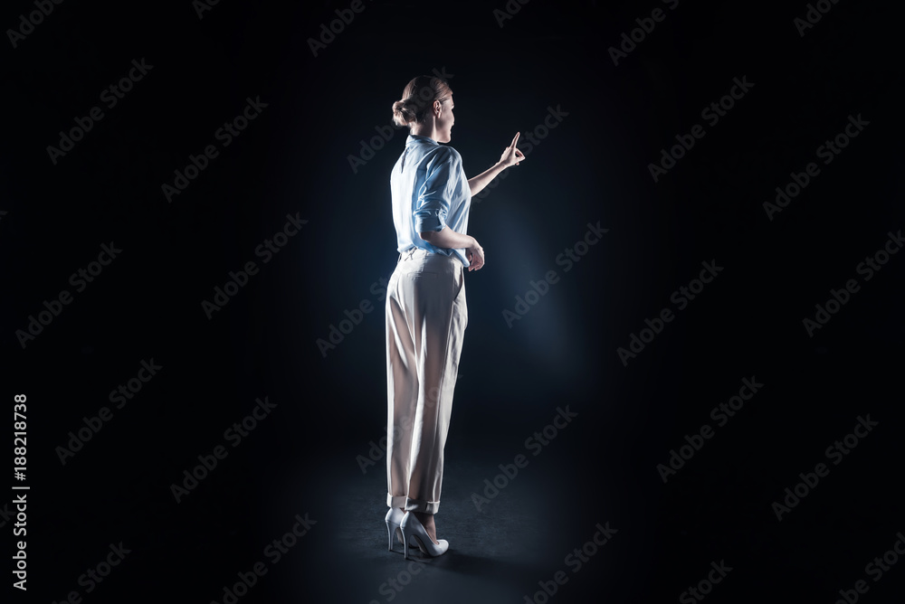 Professional tech. Positive attractive young woman looking at the virtual panel and pressing it while working