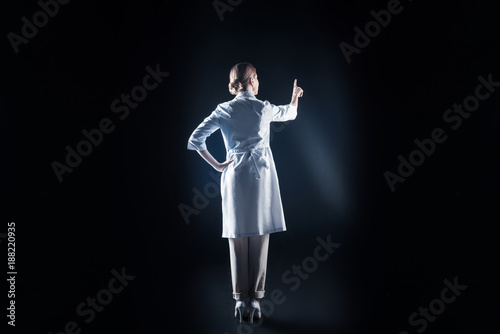 High professionalism. Smart nice female scientist wearing labcoat and using virtual screen while being at work