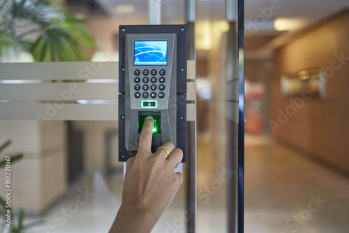 Man or woman push finger down on  electronic control machine to access security door system photo