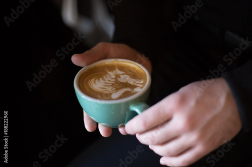 Woman holds cup with fresh coffee and funny horse blowing kiss latte art made with coffee.