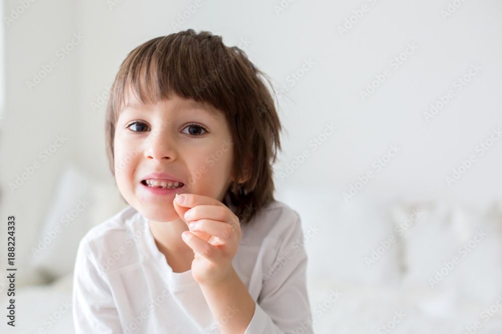 Little smiling child boy hand pointing his first baby milk tooth fall