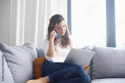 Shopping from home is comfy. A woman sitting on sofa and looking thoughtful while shopping online and banking with her credit card.
