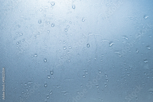 Water drops on blue frosted glass texture as background