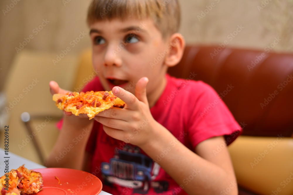 boy in red T-shirt eating pizza at home. portrait of a young man eating pizza, background boy in red T-shirt eating pizza at home. portrait of a young man eating pizza, background