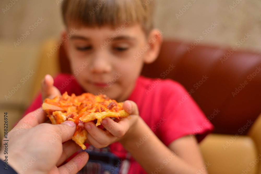 boy in red T-shirt eating pizza at home. portrait of a young man eating pizza, background boy in red T-shirt eating pizza at home. portrait of a young man eating pizza, background