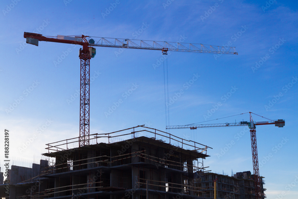 Under construction high-rise building with two cranes the background of blue sky