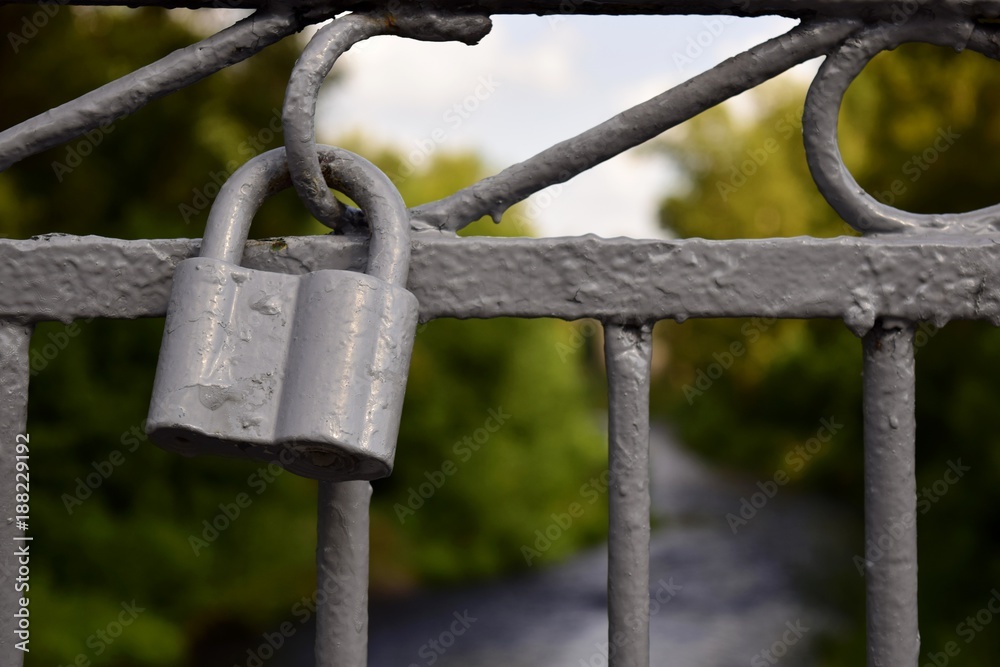 A gray old lock on a metal fence. A gray old lock on a metal fence.