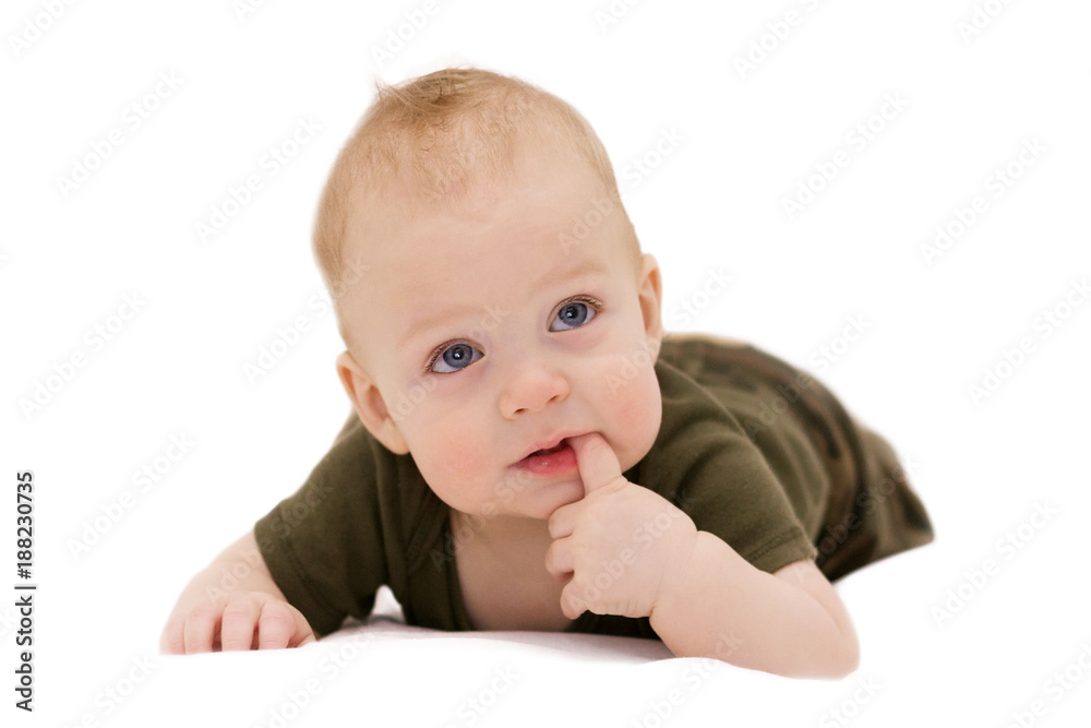 Cute blue-eyed infant boy with a finger in the mouth crawling on the white blanket against isolated white background looking at camera